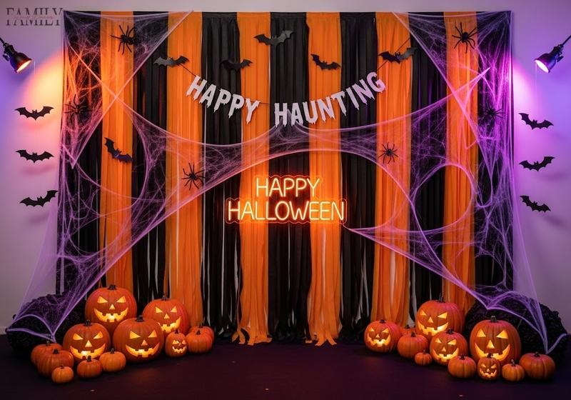Halloween photo booth backdrop with black and orange streamers, cobwebs, “Happy Haunting” banner, pumpkins, and glowing neon sign creating a festive party focal point.